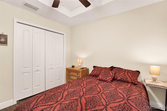 bedroom with wood finished floors, visible vents, baseboards, a ceiling fan, and a closet