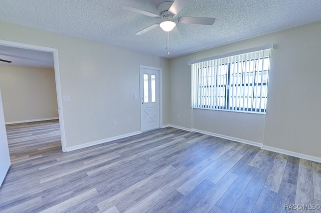 unfurnished room with a textured ceiling, light wood-type flooring, and ceiling fan