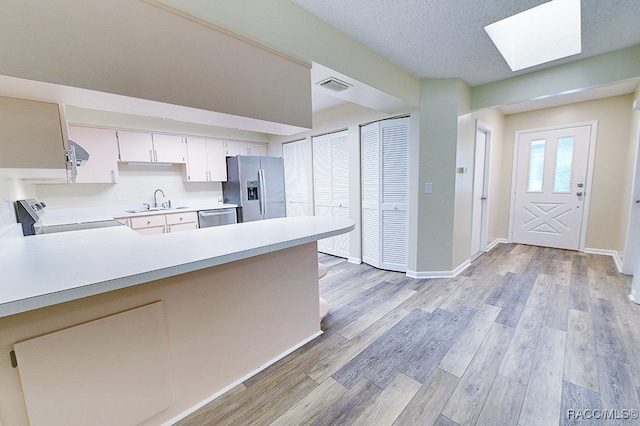 kitchen featuring kitchen peninsula, light wood-type flooring, and appliances with stainless steel finishes