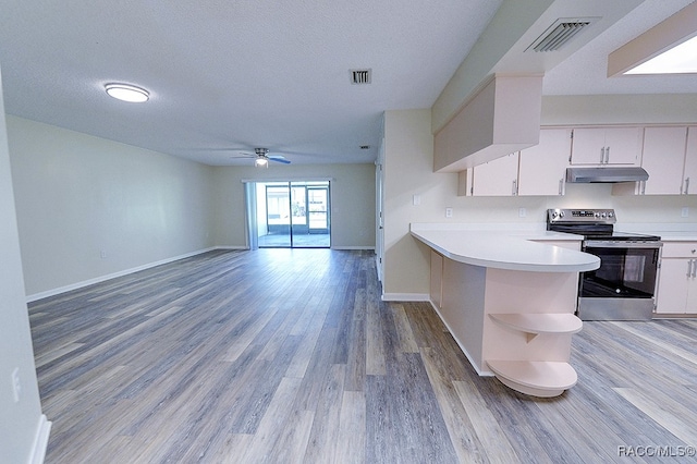 kitchen with kitchen peninsula, light wood-type flooring, stainless steel range with electric stovetop, ceiling fan, and white cabinetry