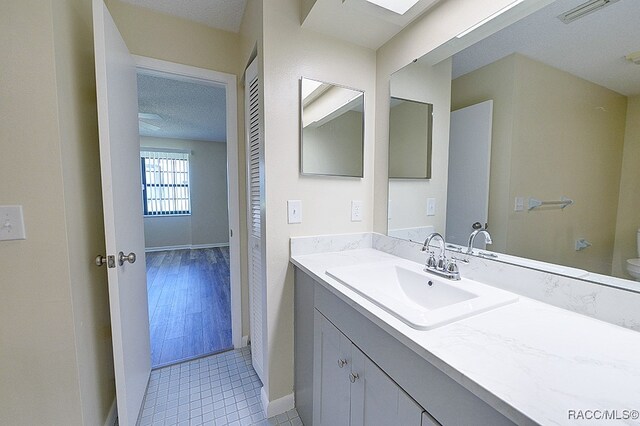 bathroom with vanity, toilet, wood-type flooring, and a textured ceiling