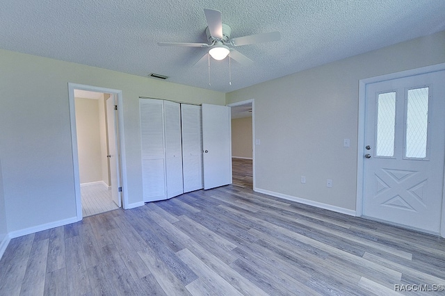 unfurnished bedroom featuring a textured ceiling, light wood-type flooring, a closet, and ceiling fan