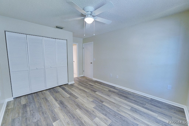 unfurnished bedroom featuring a closet, ceiling fan, light hardwood / wood-style flooring, and a textured ceiling