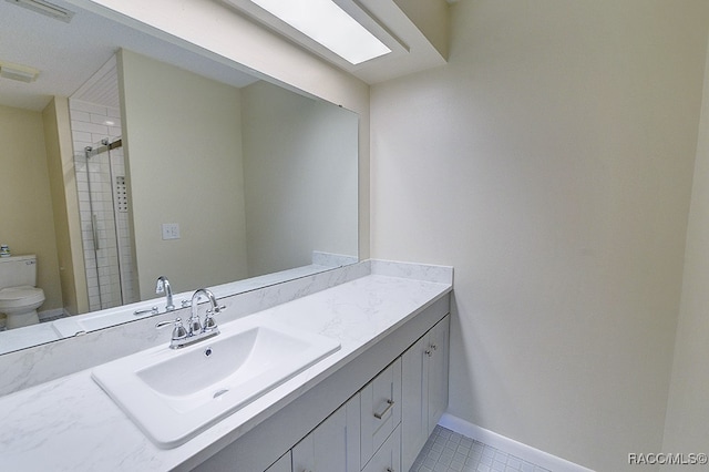 bathroom with toilet, vanity, tiled shower, and tile patterned floors