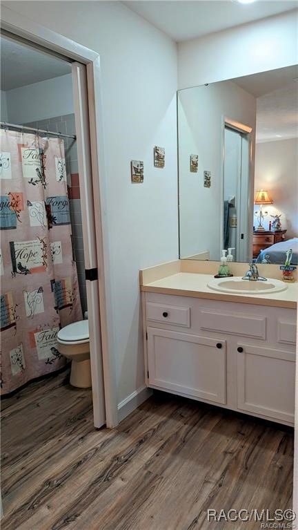 bathroom with hardwood / wood-style floors, vanity, curtained shower, and toilet