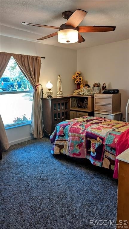 carpeted bedroom with ceiling fan and a textured ceiling