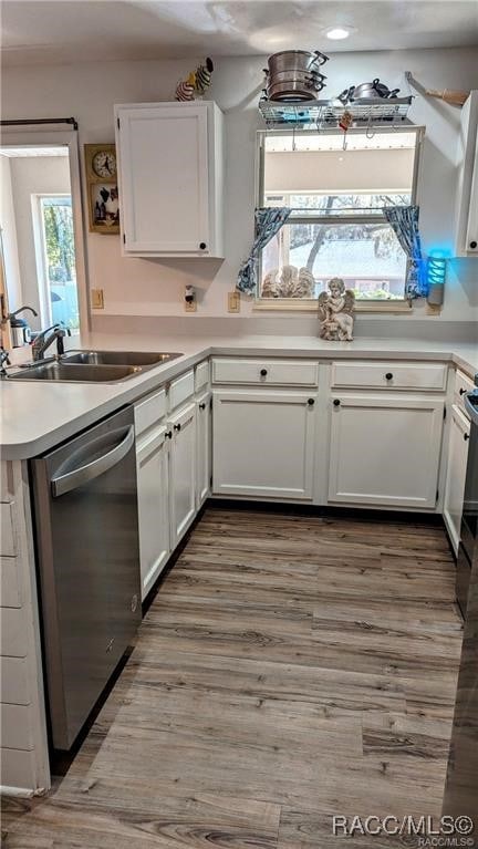 kitchen with dark hardwood / wood-style flooring, white cabinetry, stainless steel dishwasher, and sink