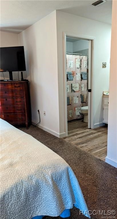 bedroom featuring ensuite bathroom and hardwood / wood-style flooring