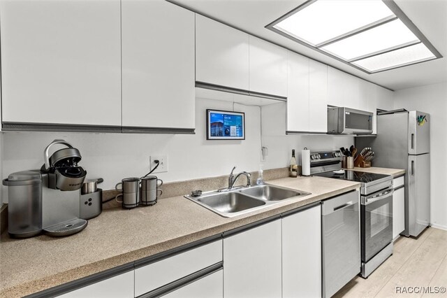 kitchen featuring light hardwood / wood-style flooring, white cabinets, stainless steel appliances, and sink