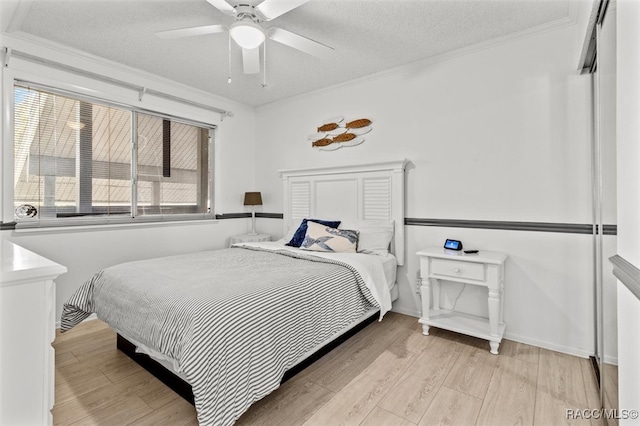 bedroom featuring a textured ceiling, light hardwood / wood-style flooring, ceiling fan, and ornamental molding