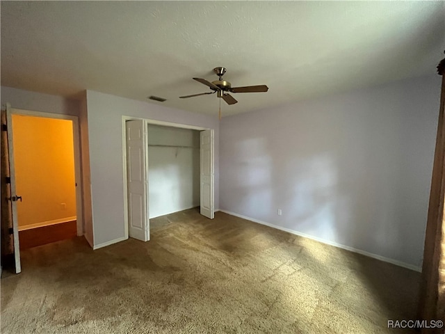 unfurnished bedroom with ceiling fan, a closet, and dark carpet