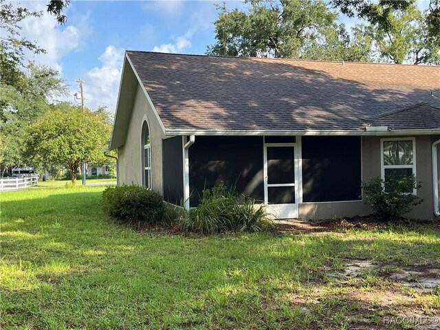 2788 W Elm Blossom St, Beverly Hills, FL 34465 - view of side of property with a sunroom, a lawn, roof with shingles, and stucco siding