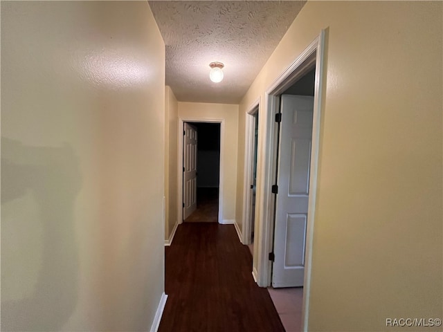 hall with a textured ceiling and dark hardwood / wood-style flooring