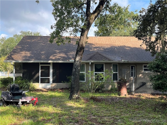 rear view of house featuring a yard and a sunroom