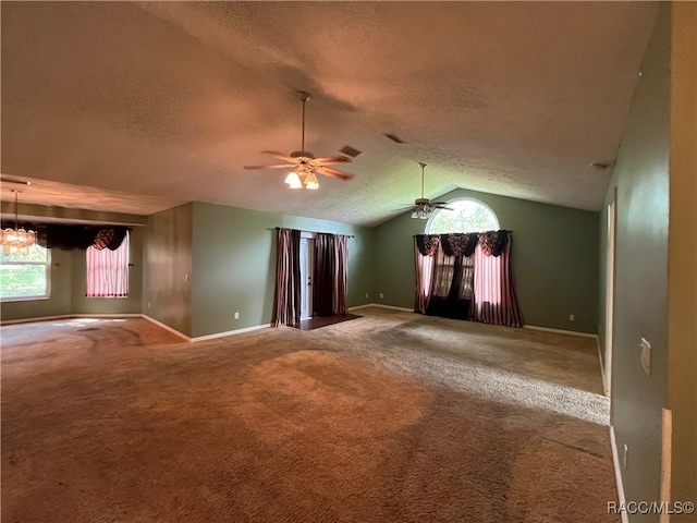 carpeted spare room with vaulted ceiling, ceiling fan with notable chandelier, and a textured ceiling