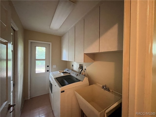 laundry area with cabinets, light tile patterned floors, washing machine and clothes dryer, and sink