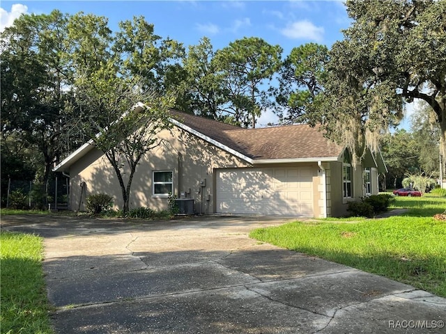 view of front of house with a front lawn, a garage, and central AC