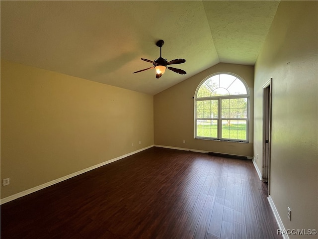 spare room featuring ceiling fan, vaulted ceiling, dark hardwood / wood-style flooring, and a textured ceiling