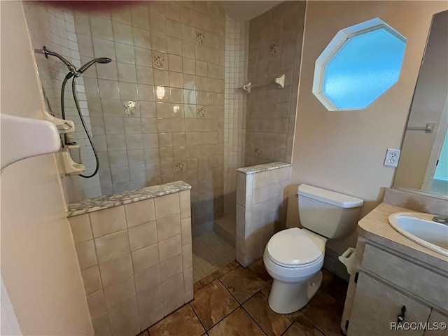 bathroom featuring tile patterned floors, vanity, a tile shower, and toilet