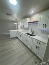 kitchen with sink, light hardwood / wood-style flooring, backsplash, kitchen peninsula, and white cabinets