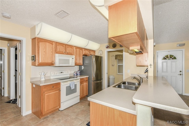 kitchen with a textured ceiling, kitchen peninsula, white appliances, and sink