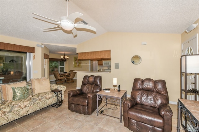 living room with ceiling fan with notable chandelier, light tile patterned floors, a textured ceiling, and vaulted ceiling