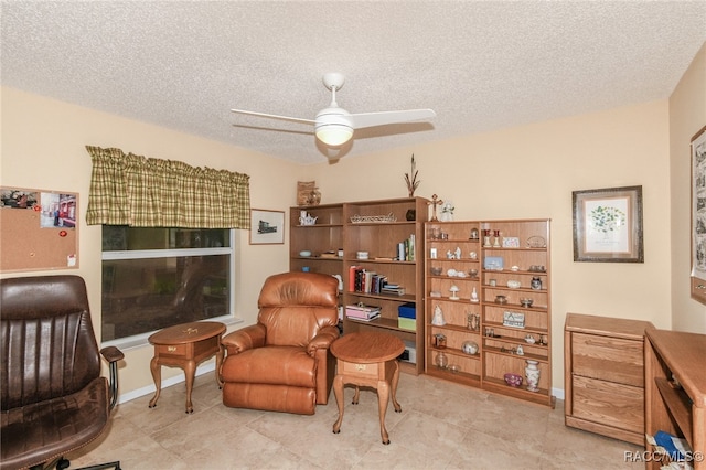 living area featuring ceiling fan and a textured ceiling