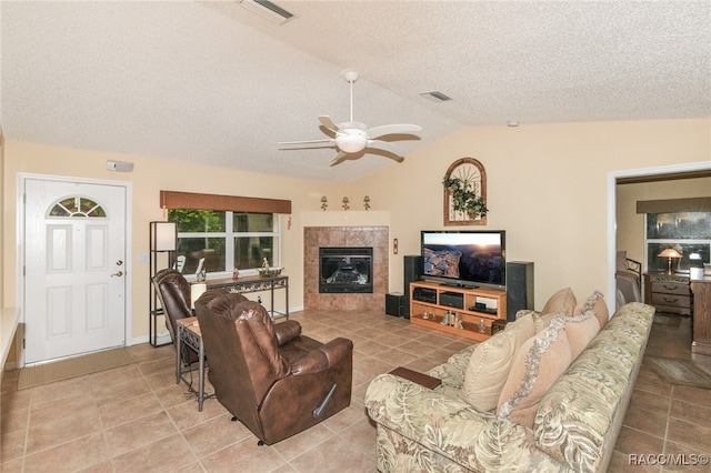 living room featuring a textured ceiling, vaulted ceiling, ceiling fan, light tile patterned floors, and a fireplace