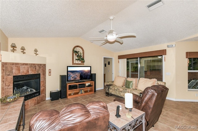 living room featuring a textured ceiling, a tiled fireplace, ceiling fan, and lofted ceiling