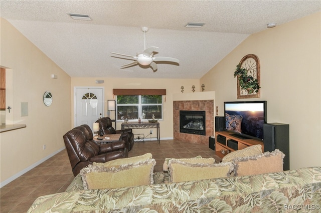 tiled living room with a textured ceiling, a tiled fireplace, ceiling fan, and lofted ceiling