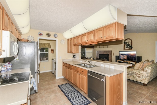 kitchen featuring white appliances, sink, light tile patterned floors, a textured ceiling, and kitchen peninsula