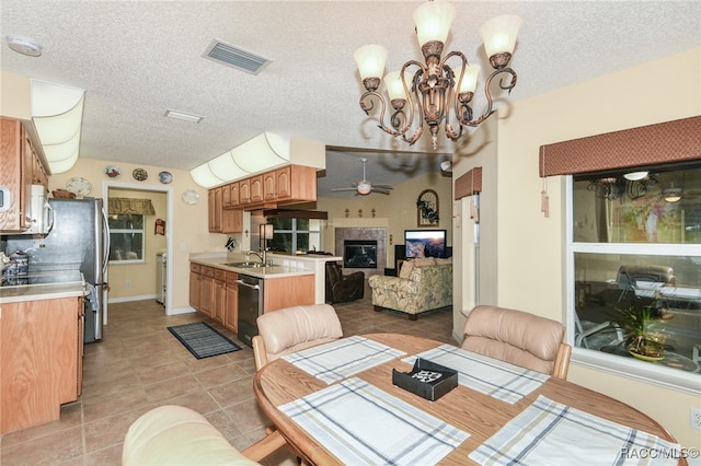 tiled dining space featuring ceiling fan with notable chandelier, sink, and a textured ceiling