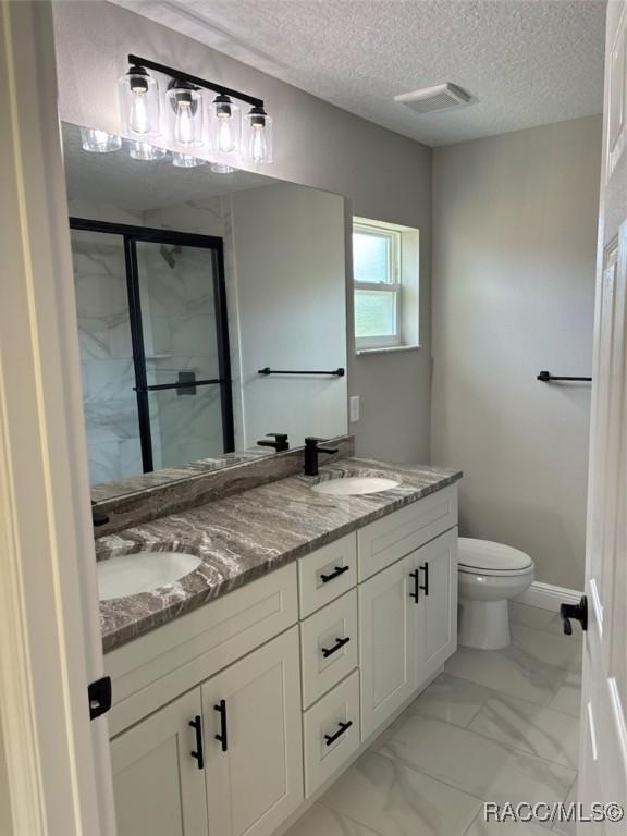 10185 N Halsey Way, Citrus Springs, FL 34434 - bathroom with toilet, double vanity, a shower stall, marble look tile flooring, and a textured ceiling