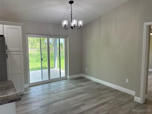 10185 N Halsey Way, Citrus Springs, FL 34434 - unfurnished dining area with a chandelier, baseboards, a textured ceiling, and light wood-style flooring