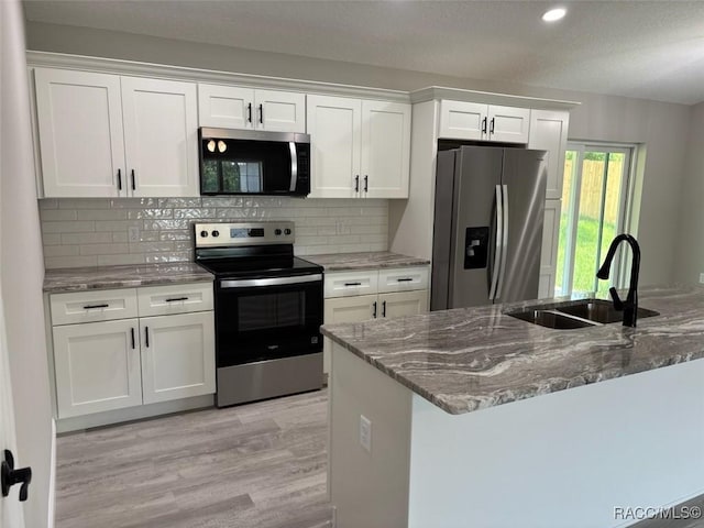 10185 N Halsey Way, Citrus Springs, FL 34434 - kitchen with appliances with stainless steel finishes, a sink, white cabinetry, light wood-style floors, and stone counters