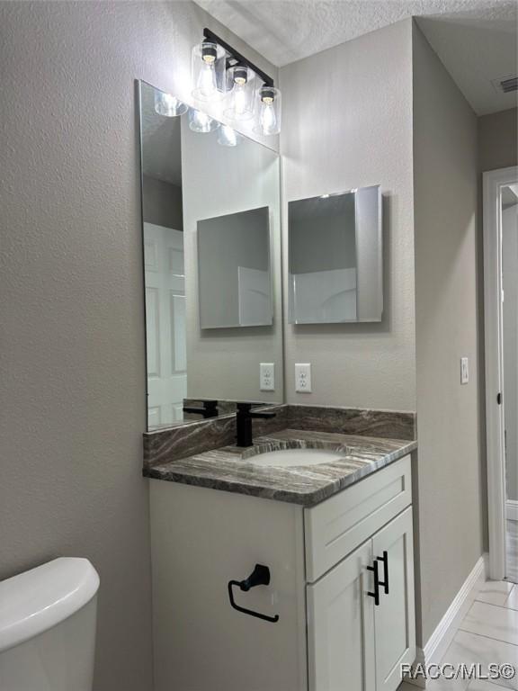 10185 N Halsey Way, Citrus Springs, FL 34434 - half bathroom with vanity, toilet, and a textured ceiling