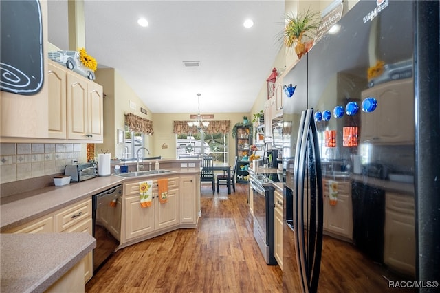 kitchen with vaulted ceiling, sink, black dishwasher, stainless steel stove, and hanging light fixtures