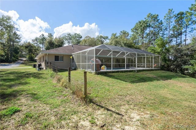 rear view of house with glass enclosure and a lawn