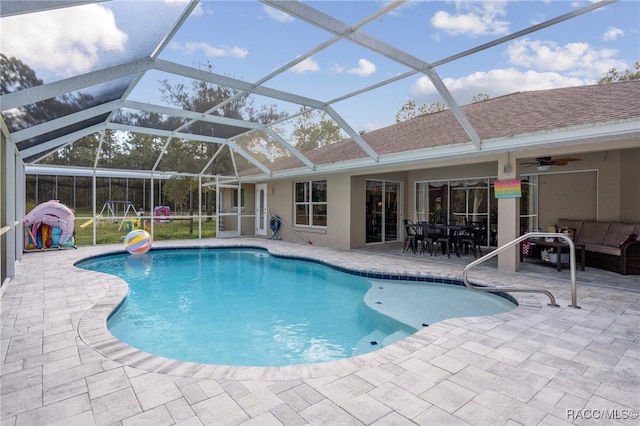 view of pool with an outdoor hangout area, glass enclosure, ceiling fan, and a patio area