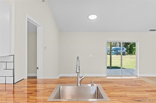 kitchen featuring wood-type flooring, lofted ceiling, and sink