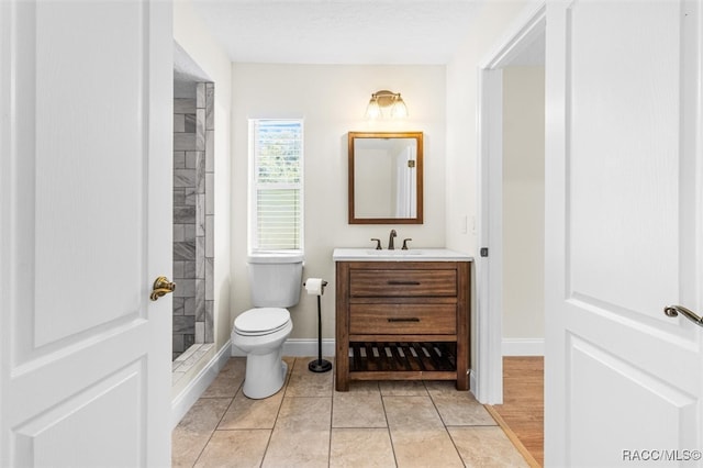 bathroom with tile patterned flooring, a shower, vanity, and toilet