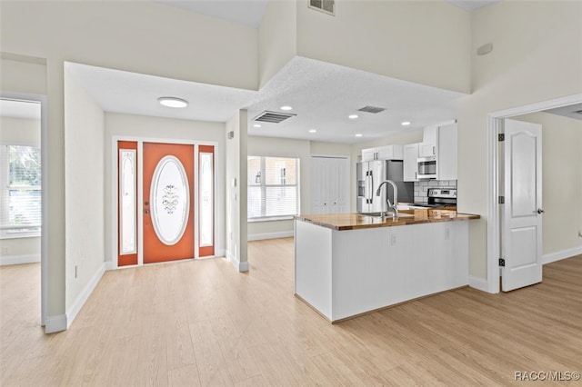 kitchen with tasteful backsplash, stainless steel appliances, sink, light hardwood / wood-style floors, and white cabinetry