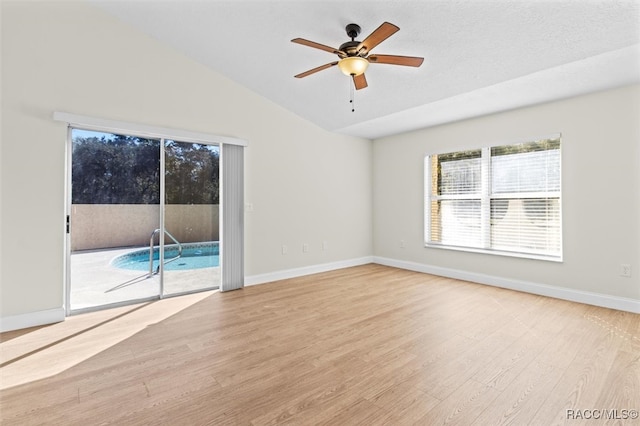 empty room with a textured ceiling, light hardwood / wood-style floors, ceiling fan, and lofted ceiling