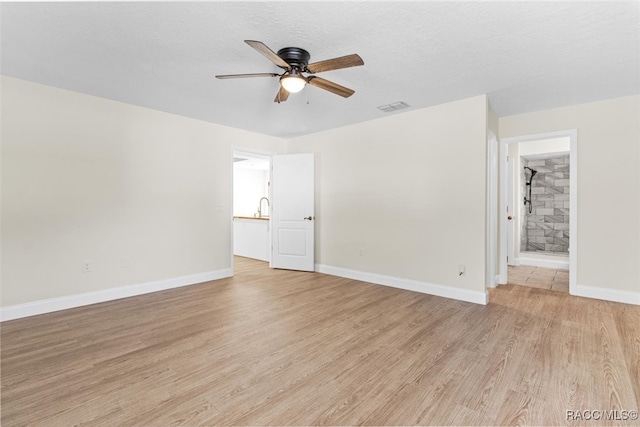 unfurnished room featuring ceiling fan, light wood-type flooring, and a textured ceiling