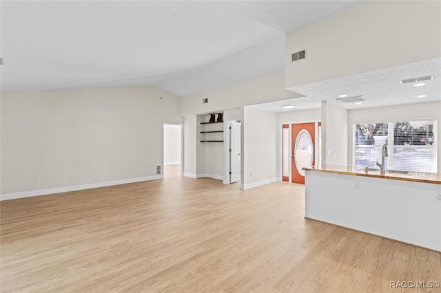 unfurnished living room featuring light hardwood / wood-style flooring, vaulted ceiling, and sink