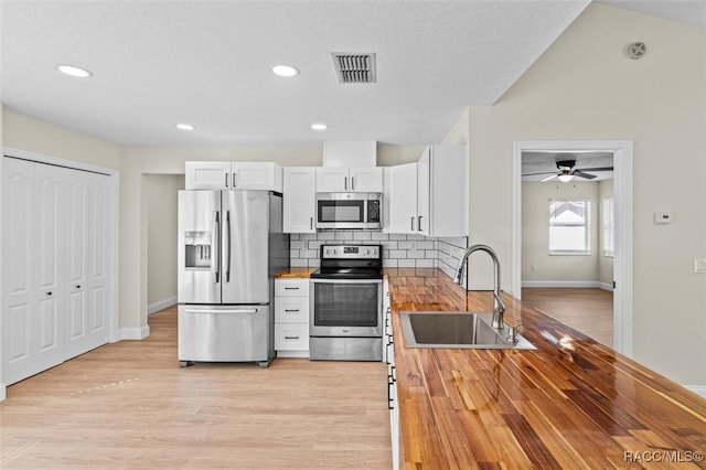 kitchen with wood counters, white cabinetry, sink, and appliances with stainless steel finishes