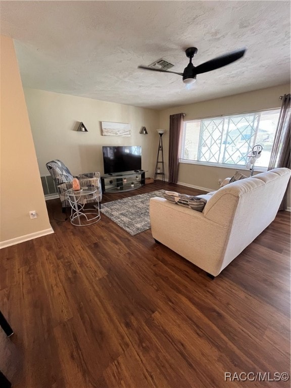 living room featuring a textured ceiling, ceiling fan, and dark wood-type flooring