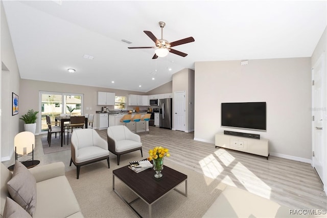 living room with light hardwood / wood-style floors, high vaulted ceiling, and ceiling fan