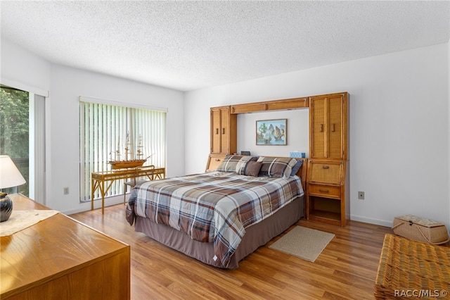 bedroom with light wood-type flooring and a textured ceiling