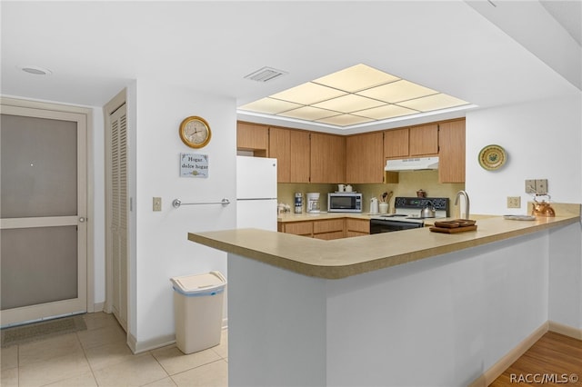 kitchen featuring kitchen peninsula, light tile patterned floors, and white appliances